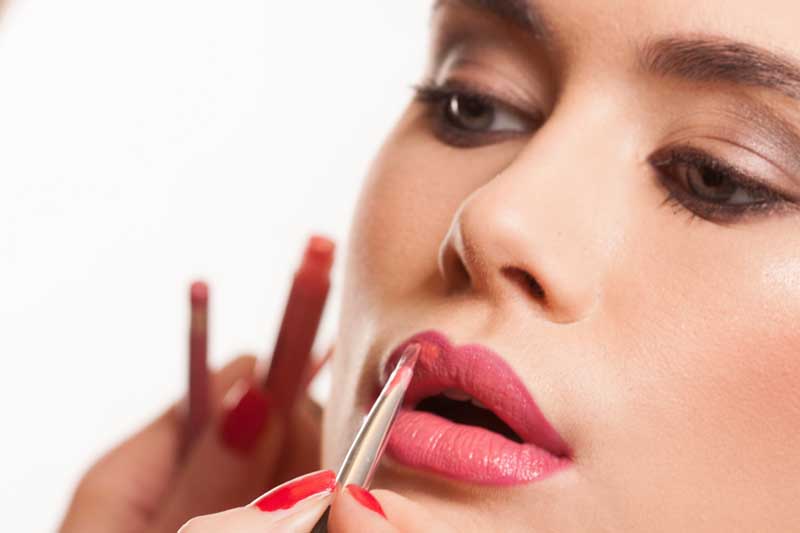 عکس با کیفیت خانم در حال زدن رژ لب
